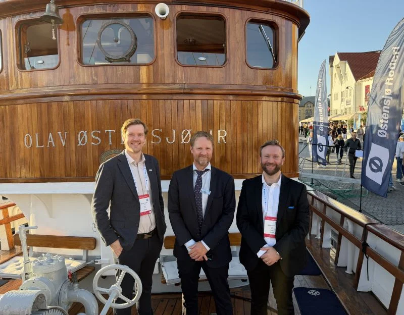 Three people on deck beside the Olav Østensjø vessel name.
